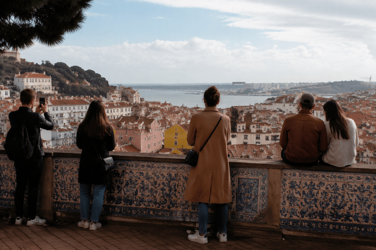 Visitors looking over Lisbon’s rooftops and river from a hillside viewpoint.